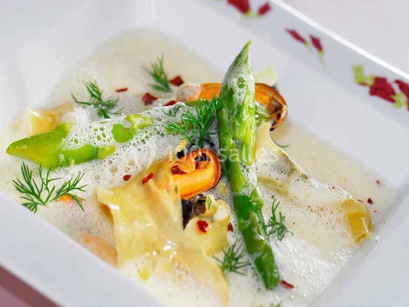 Assiette de pâtes garnie d'asperges vertes, moules, aneth et sauce crémeuse.