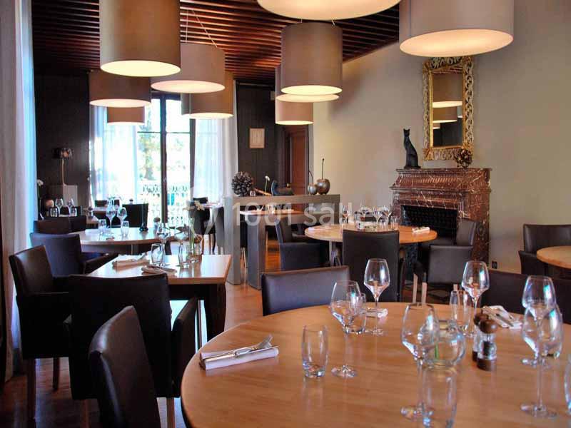 Salle de restaurant élégante avec tables en bois, chaises en cuir, lustres modernes et cheminée décorative.