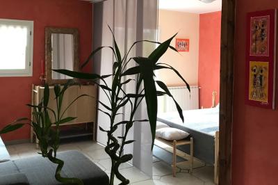 Structure en bois triangulaire devant des bancs disposés en plein air sur une pelouse entourée d'arbres.