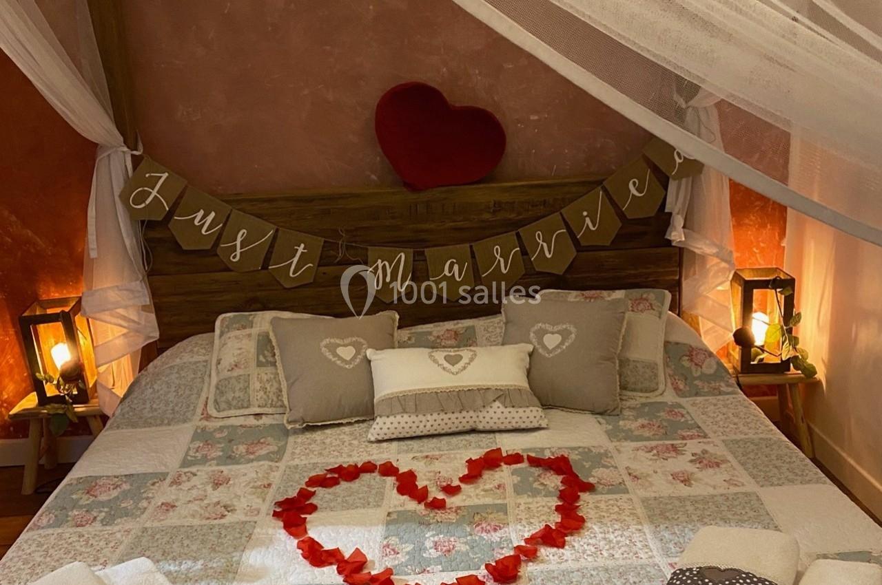 Lit décoré avec des pétales de rose en forme de cœur, guirlande ’Just married’ et lumière tamisée.