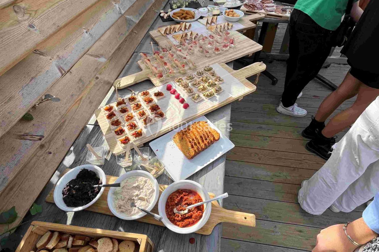 Buffet en extérieur avec divers plats, toasts, tartinades et amuse-bouches présentés sur une table en bois.