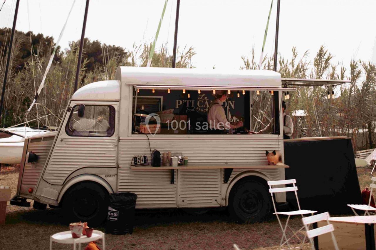 Camion-restaurant vintage stationné en extérieur, avec un cuisinier préparant des plats derrière le comptoir.