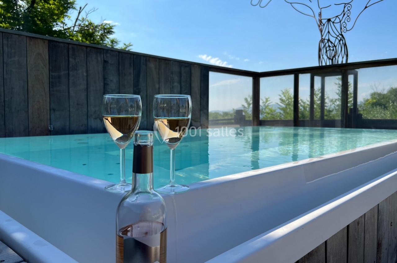 Trois verres de vin rosé et une bouteille posés au bord d'une piscine extérieure sous un ciel dégagé.