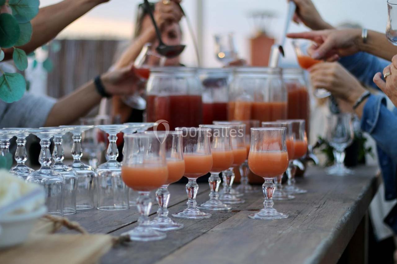 Des verres de cocktail remplis sur une table en bois, entourés de mains servant des boissons.