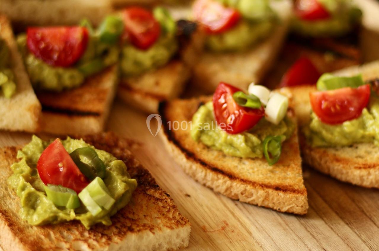 Tranches de pain grillé garnies de guacamole, de tomates cerises et de rondelles d'oignons verts.