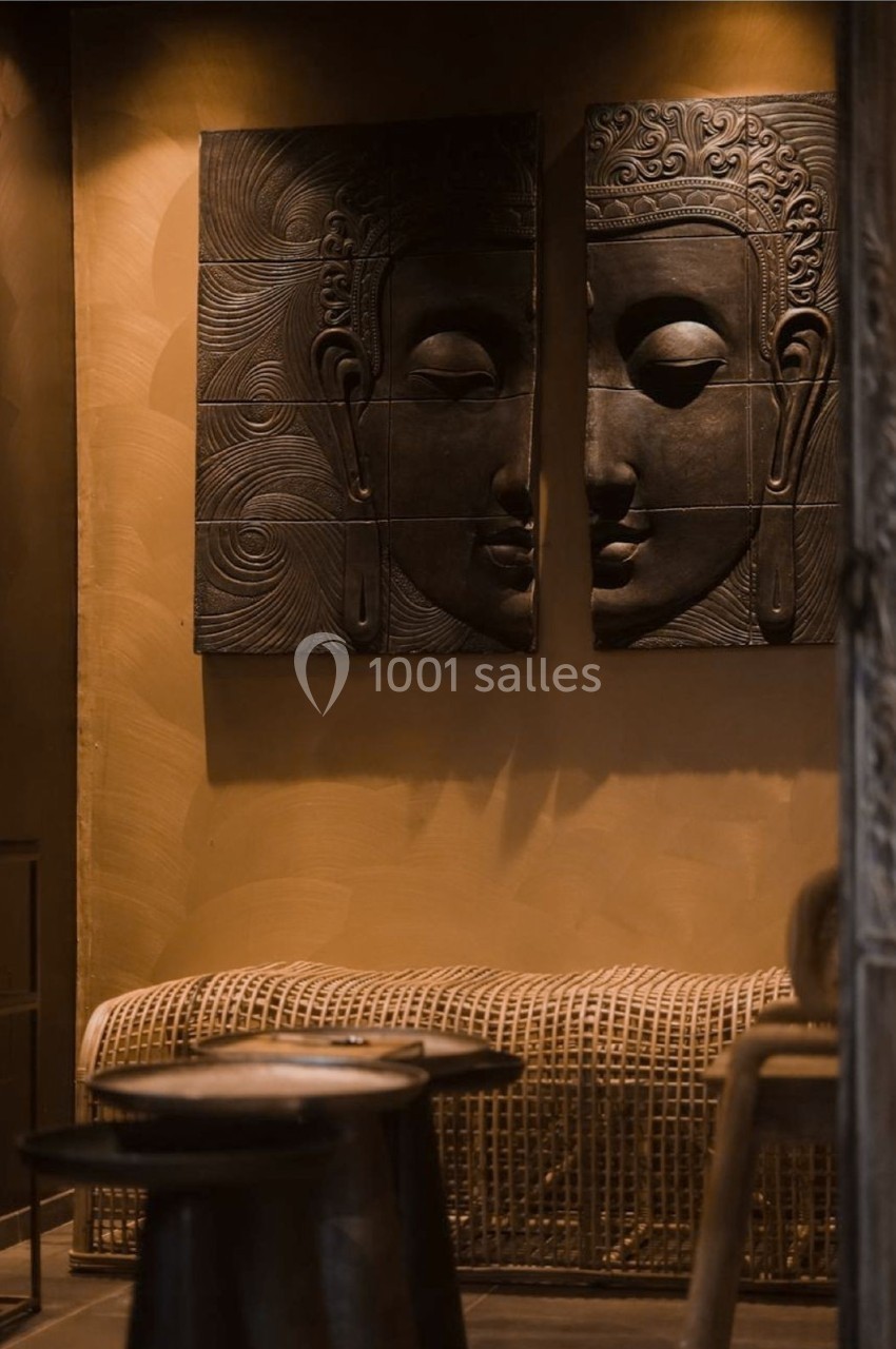 Deux panneaux muraux sculptés représentant des visages de Bouddha, décorant un espace intérieur chaleureux et tamisé.