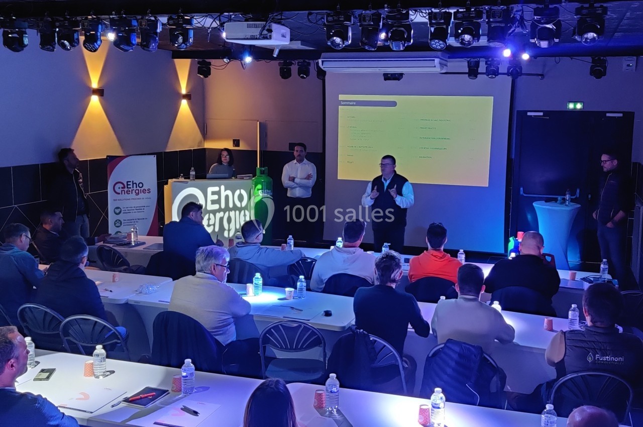 Un conférencier s'adresse à un public assis dans une salle éclairée, avec un écran de présentation en arrière-plan.