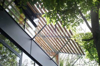 Salle de réunion lumineuse avec table en bois, quatre chaises noires, écran mural et cloison vitrée donnant sur l'extérieur.