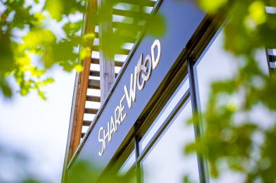 Salle de réunion lumineuse avec table en bois, quatre chaises noires, écran mural et cloison vitrée donnant sur l'extérieur.