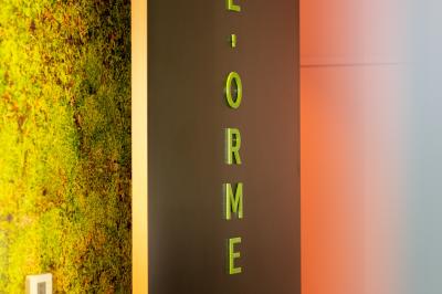 Salle de réunion lumineuse avec table en bois, quatre chaises noires, écran mural et cloison vitrée donnant sur l'extérieur.