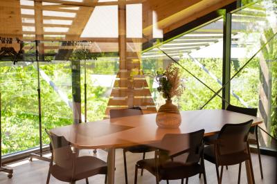 Salle de réunion lumineuse avec table en bois, quatre chaises noires, écran mural et cloison vitrée donnant sur l'extérieur.