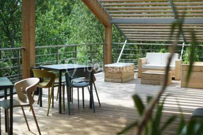 Salle de réunion lumineuse avec table en bois, quatre chaises noires, écran mural et cloison vitrée donnant sur l'extérieur.