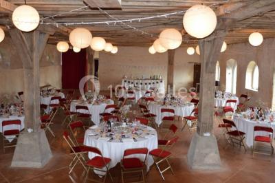 Voitures garées en file sur un terrain herbeux entouré d'arbres par une journée ensoleillée.