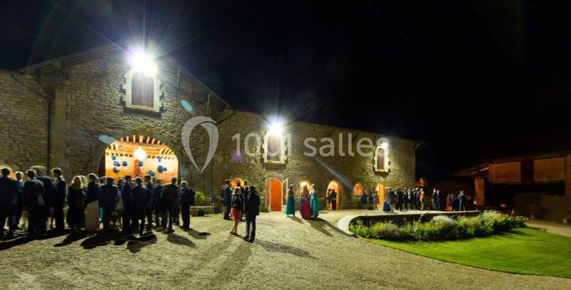 Façade éclairée d'un bâtiment en pierre la nuit, avec des invités rassemblés devant pour un événement.