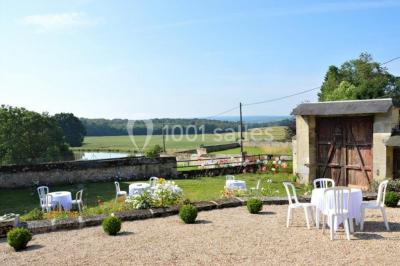 Voitures garées en file sur un terrain herbeux entouré d'arbres par une journée ensoleillée.