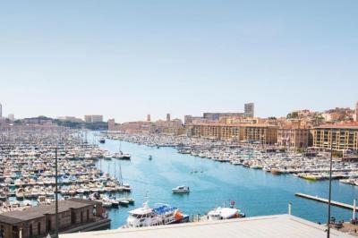 Cabine de bateau avec deux lits simples, linge de lit beige et rouge, éclairage intégré et hublots.