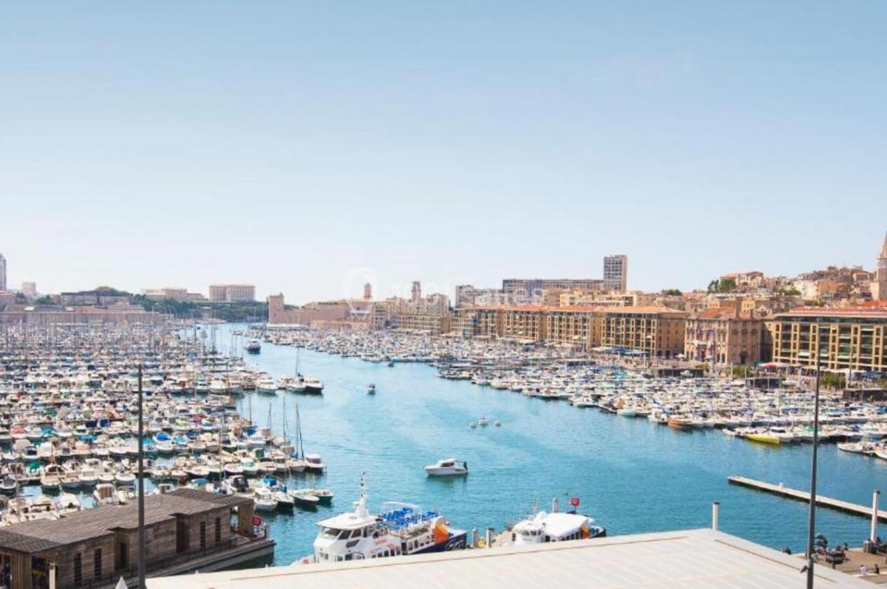Vue sur un port rempli de nombreux bateaux, entouré de bâtiments et d'une ville sous un ciel dégagé.