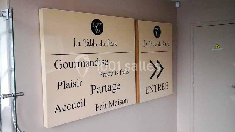 Panneaux muraux indiquant l'entrée d'un restaurant nommé ’La Table du Parc’, avec des mots-clés et une flèche directionnelle.
