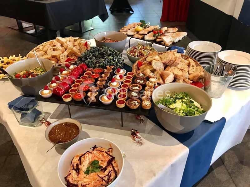 Buffet varié avec plats froids, salades, pains, desserts et sauces disposés sur une table.