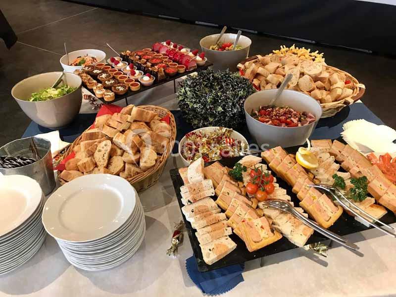 Buffet varié avec pains, salades, sandwiches, verrines et desserts disposés sur une table.