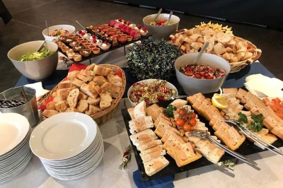 Terrasse de restaurant avec tables en bois, nappes rouges, couverts et verres, entourée de chaises en osier.