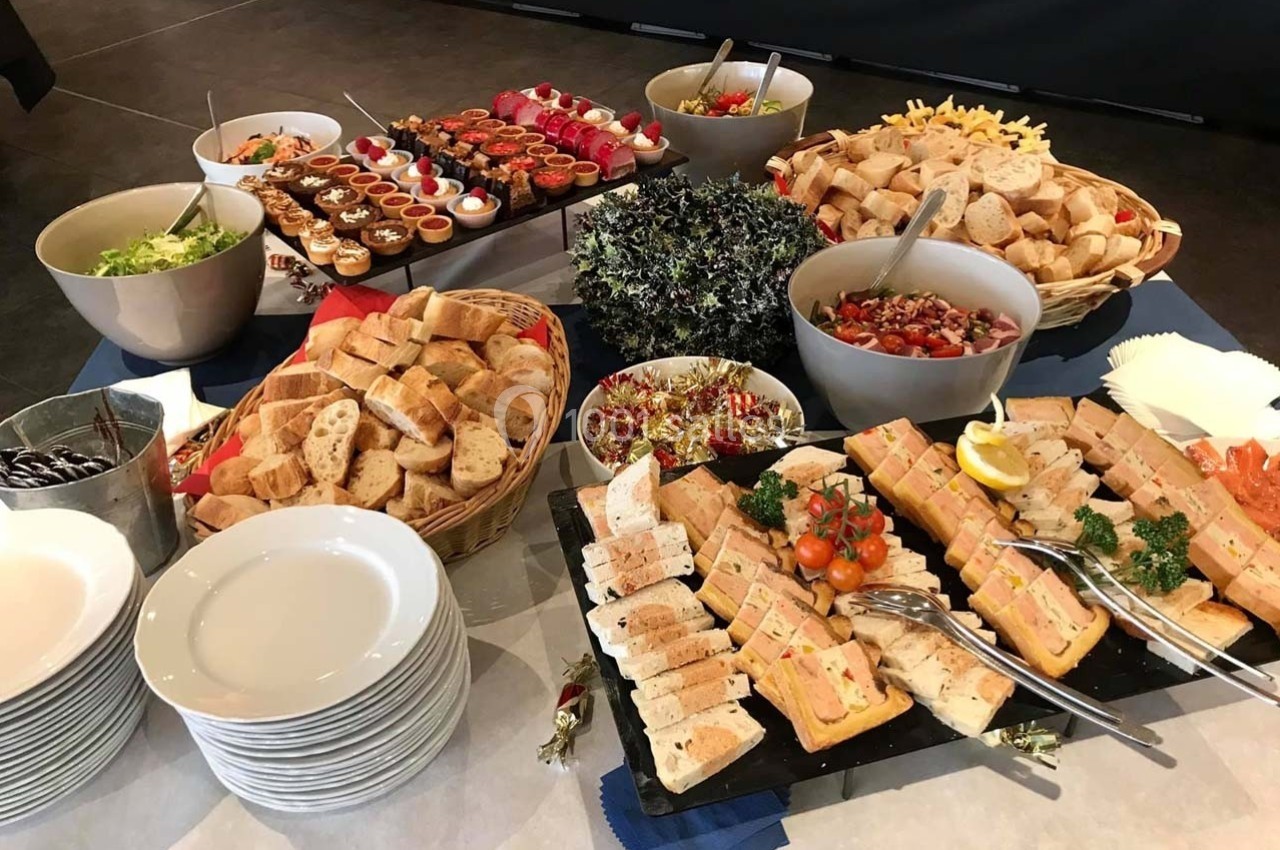 Buffet varié avec pains, salades, verrines, terrines et autres plats disposés sur une table.