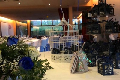 Terrasse de restaurant avec tables en bois, nappes rouges, couverts et verres, entourée de chaises en osier.