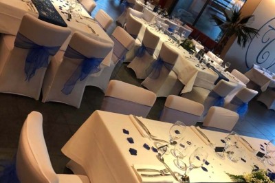 Terrasse de restaurant avec tables en bois, nappes rouges, couverts et verres, entourée de chaises en osier.