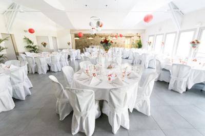 Maison blanche à étage avec escalier extérieur en bois, cabanon en bois à côté, jardin fleuri et clôture en bois.