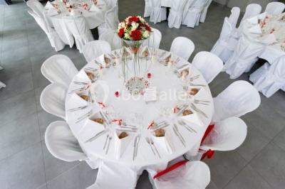 Maison blanche à étage avec escalier extérieur en bois, cabanon en bois à côté, jardin fleuri et clôture en bois.