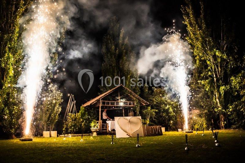 Feux d'artifice illuminant un jardin de nuit avec une structure en bois et une décoration en forme de cœur.