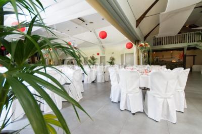 Maison blanche à étage avec escalier extérieur en bois, cabanon en bois à côté, jardin fleuri et clôture en bois.