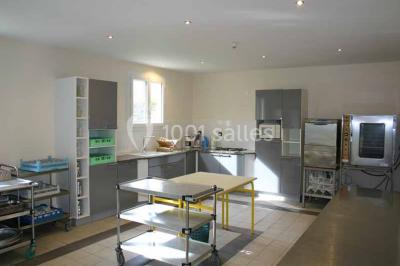 Vue d'un couloir lumineux menant à une chambre avec un lit, des murs clairs et un tapis au sol.