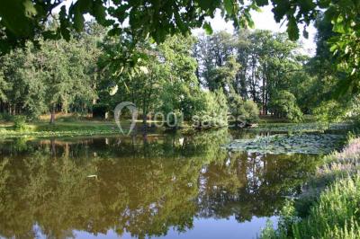 Vue d'un couloir lumineux menant à une chambre avec un lit, des murs clairs et un tapis au sol.