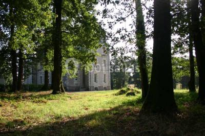 Vue d'un couloir lumineux menant à une chambre avec un lit, des murs clairs et un tapis au sol.