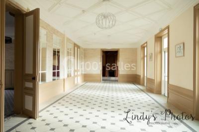 Vue d'un couloir lumineux menant à une chambre avec un lit, des murs clairs et un tapis au sol.