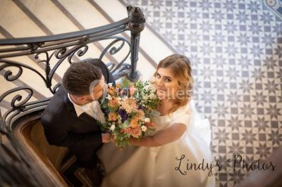 Vue d'un couloir lumineux menant à une chambre avec un lit, des murs clairs et un tapis au sol.