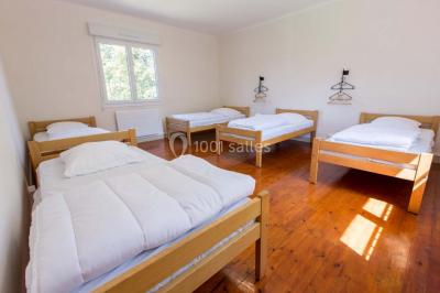 Vue d'un couloir lumineux menant à une chambre avec un lit, des murs clairs et un tapis au sol.