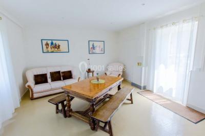 Vue d'un couloir lumineux menant à une chambre avec un lit, des murs clairs et un tapis au sol.