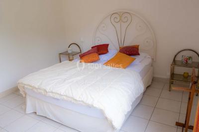 Vue d'un couloir lumineux menant à une chambre avec un lit, des murs clairs et un tapis au sol.