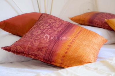 Vue d'un couloir lumineux menant à une chambre avec un lit, des murs clairs et un tapis au sol.