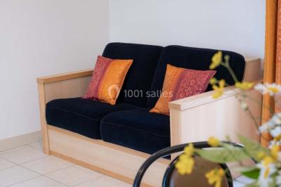 Vue d'un couloir lumineux menant à une chambre avec un lit, des murs clairs et un tapis au sol.