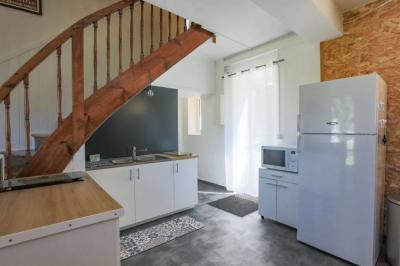 Vue d'un couloir lumineux menant à une chambre avec un lit, des murs clairs et un tapis au sol.