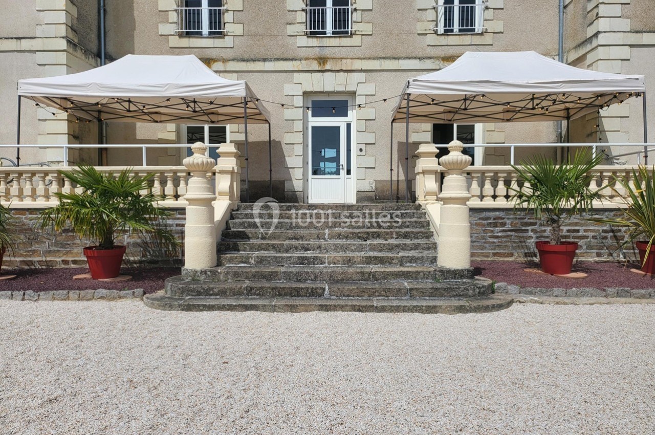 Escalier en pierre menant à une entrée avec deux tonnelles blanches et des plantes en pots de chaque côté.