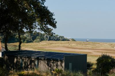 Salle de bain moderne avec meuble en bois clair, lavabo, miroir et douche vitrée équipée d'une pomme de douche.