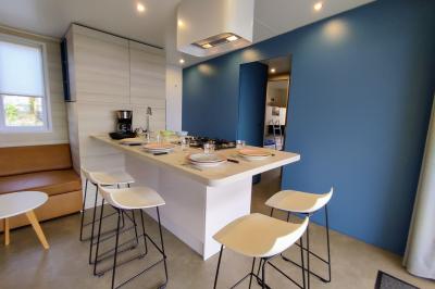 Salle de bain moderne avec meuble en bois clair, lavabo, miroir et douche vitrée équipée d'une pomme de douche.
