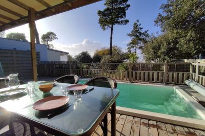 Salle de bain moderne avec meuble en bois clair, lavabo, miroir et douche vitrée équipée d'une pomme de douche.