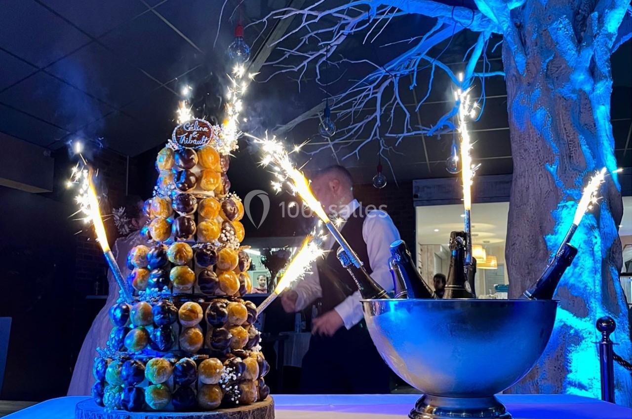 Pièce montée éclairée par des cierges magiques, accompagnée d'un seau à champagne, dans une ambiance festive.