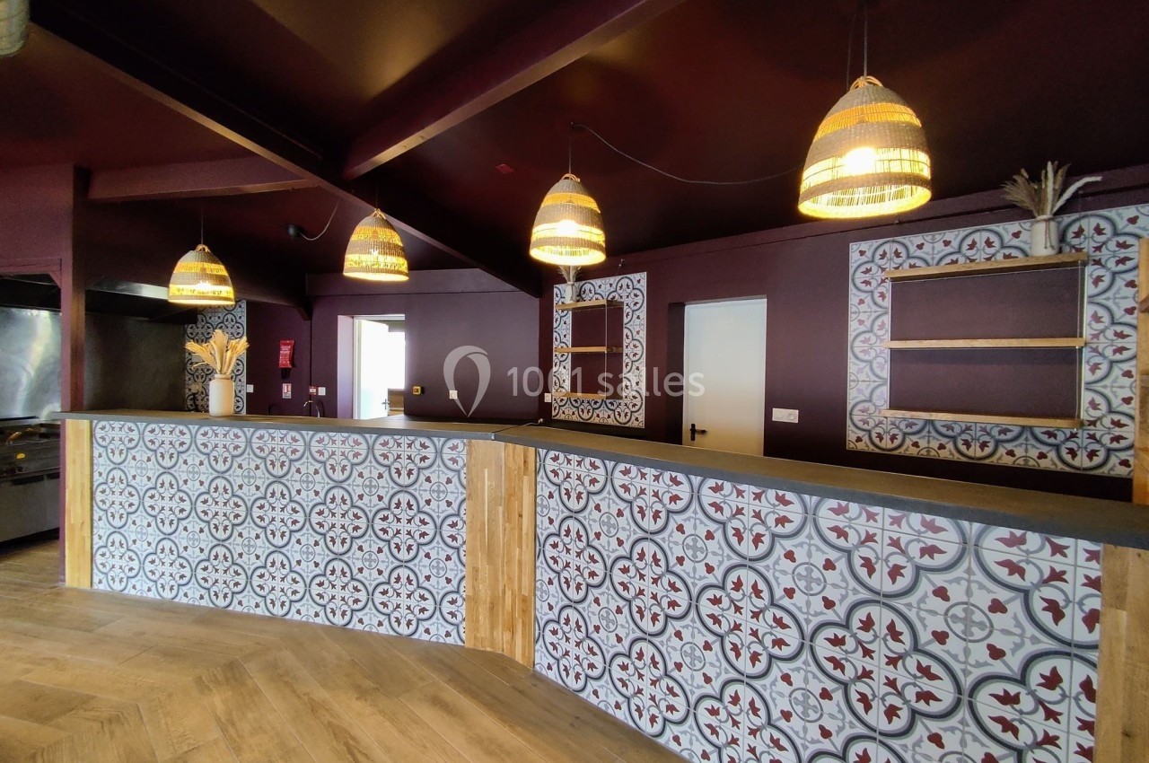 Comptoir en bois et carrelage décoratif dans un intérieur avec murs bordeaux et suspensions en osier.