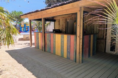 Salle de bain moderne avec meuble en bois clair, lavabo, miroir et douche vitrée équipée d'une pomme de douche.